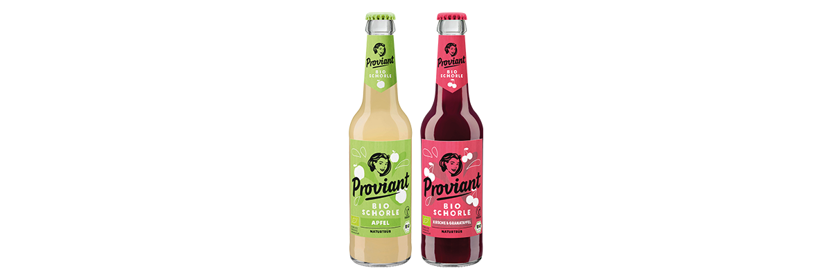 Zwei Flaschen Proviant Bio Schorle, eine Apfel in hellgrünem Etikett, eine Kirsche & Granatapfel in pinkfarbenem Etikett. Beide Flaschen sind naturtrüb.